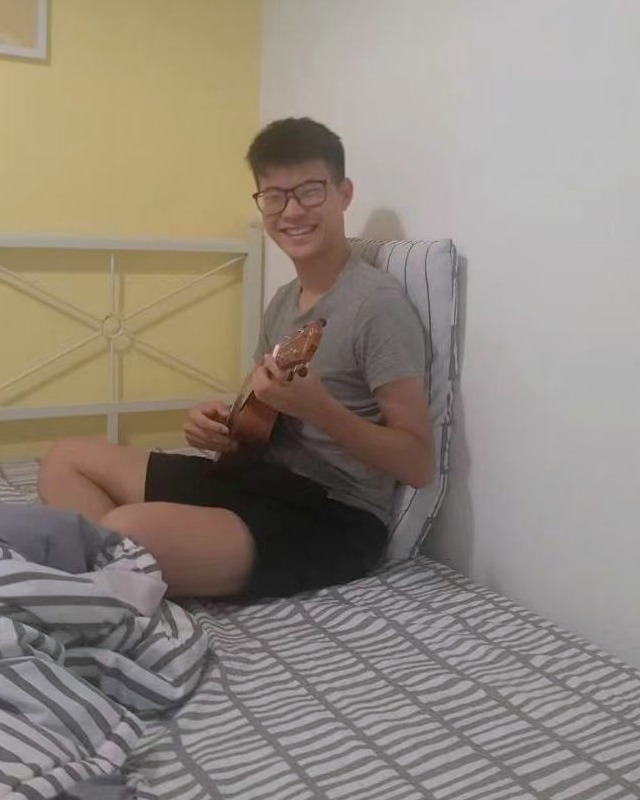 Jackie 坐着弹琴,笑着看向镜头